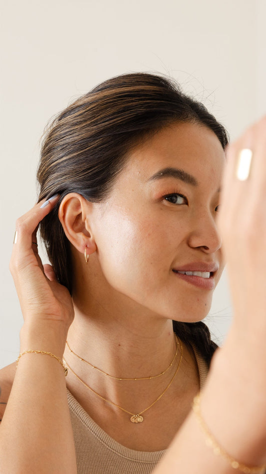 A close-up of a woman wearing a polished gold hoop earring.