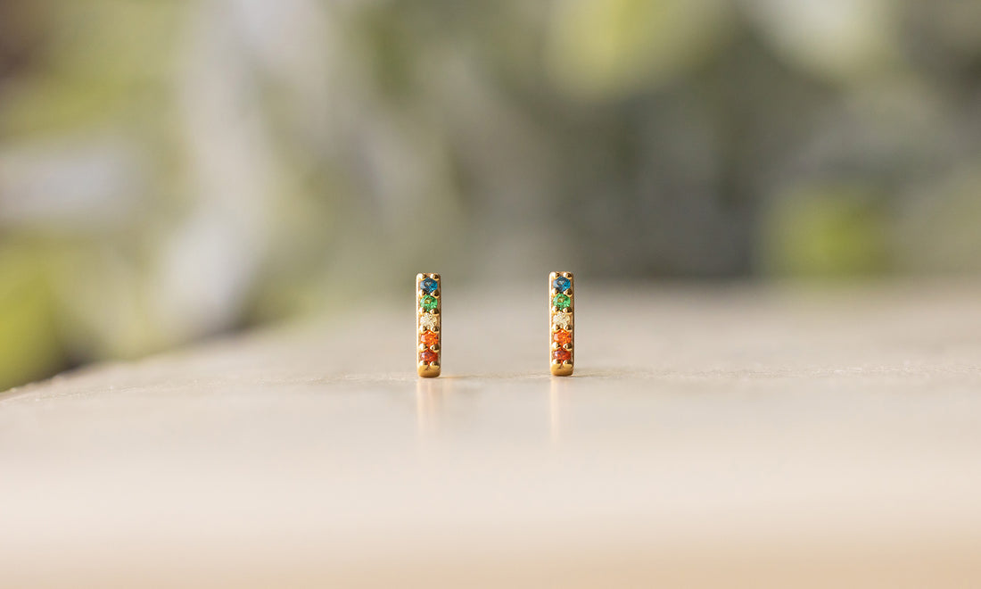 A pair of bar stud earrings with a rainbow of gemstones.