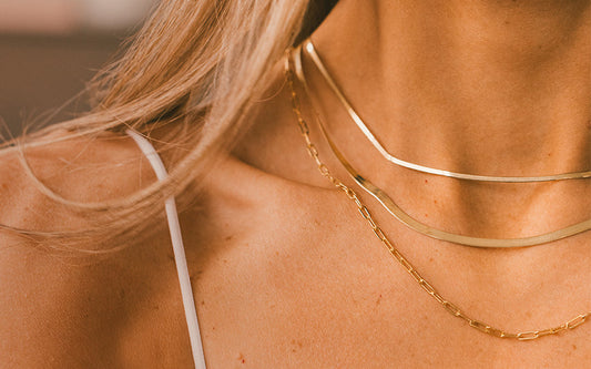 A woman wearing three layered gold chain necklaces.