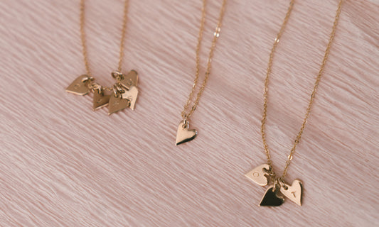 Three gold pendant necklaces with multiple small heart charms.