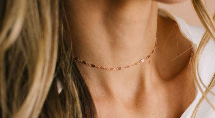 A woman wearing a delicate textured rose gold chain choker.
