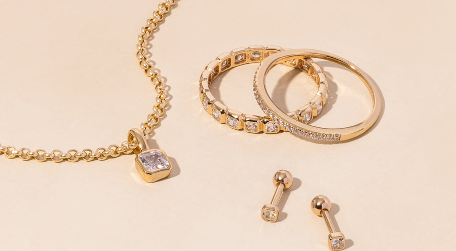 A gold necklace, rings, and earrings all adorned with clear gemstones.