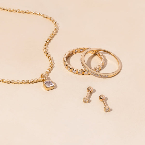 A gold necklace, rings, and earrings all adorned with clear gemstones.