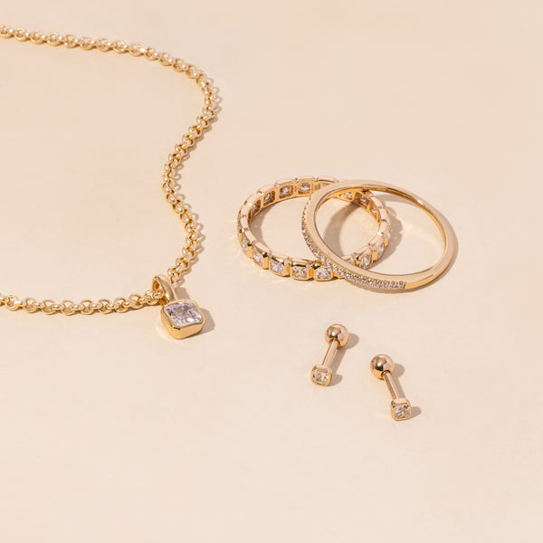 A gold necklace, rings, and earrings all adorned with clear gemstones.
