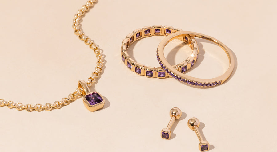 A gold necklace, rings, and earrings all adorned with purple gemstones.