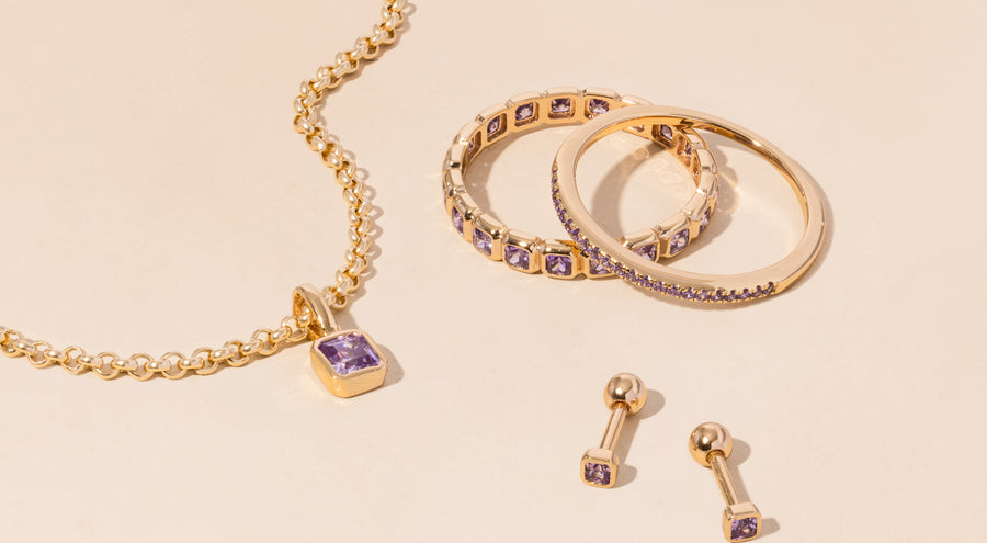A gold necklace, rings, and earrings all adorned with light purple gemstones.