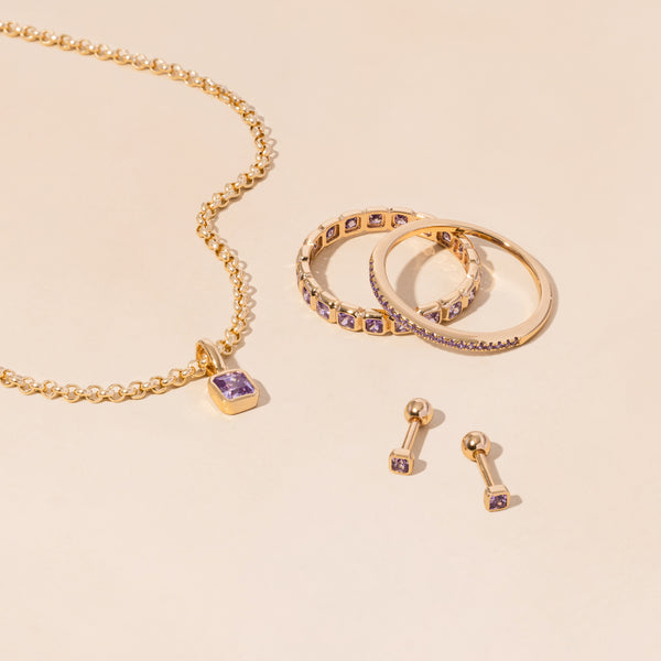 A gold necklace, rings, and earrings all adorned with light purple gemstones.