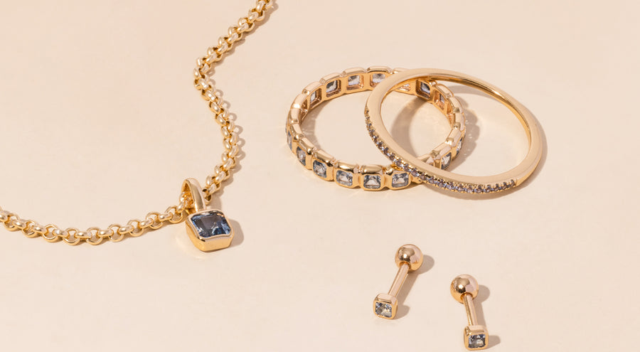 A gold necklace, rings, and earrings all adorned with light blue gemstones.