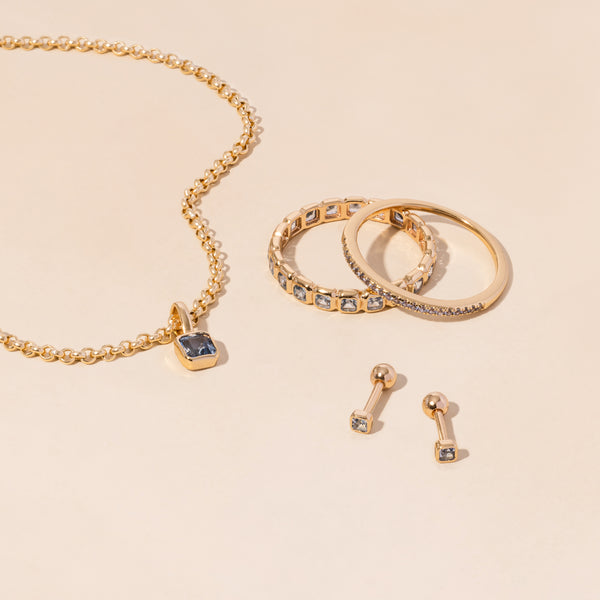 A gold necklace, rings, and earrings all adorned with light blue gemstones.