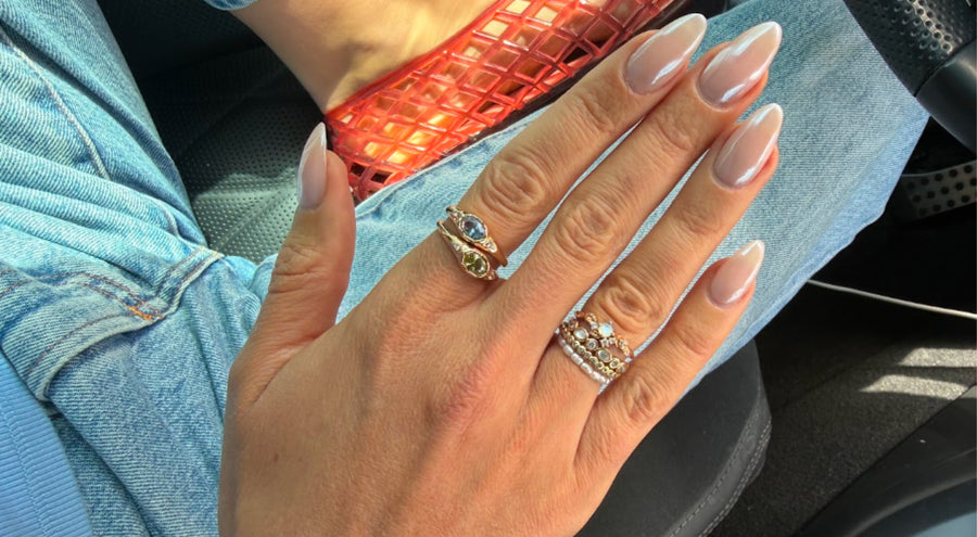 A person's hand with stacks of multiple different gold rings.