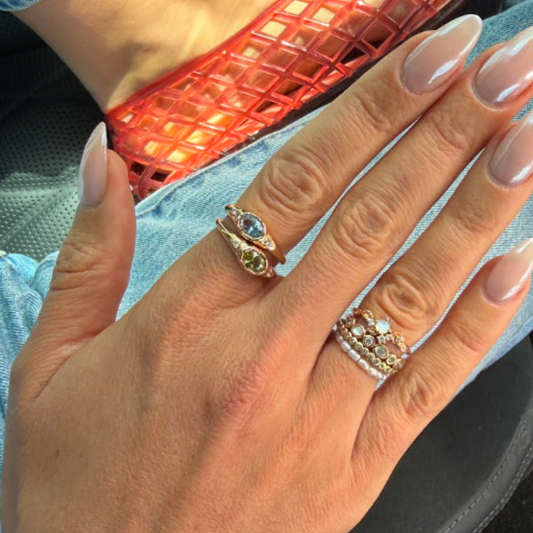 A person's hand with stacks of multiple different gold rings.