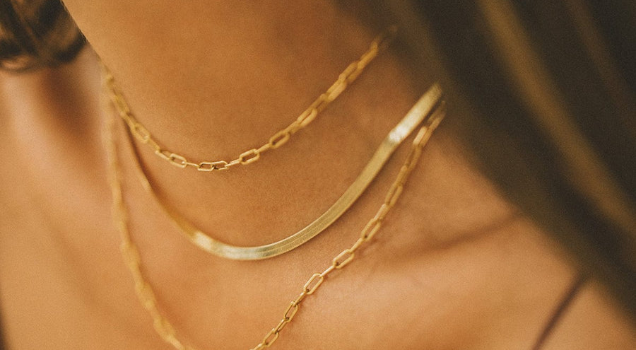 A woman wearing three layered gold chain necklaces.
