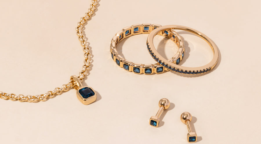 A gold necklace, rings, and earrings all adorned with blue green gemstones.