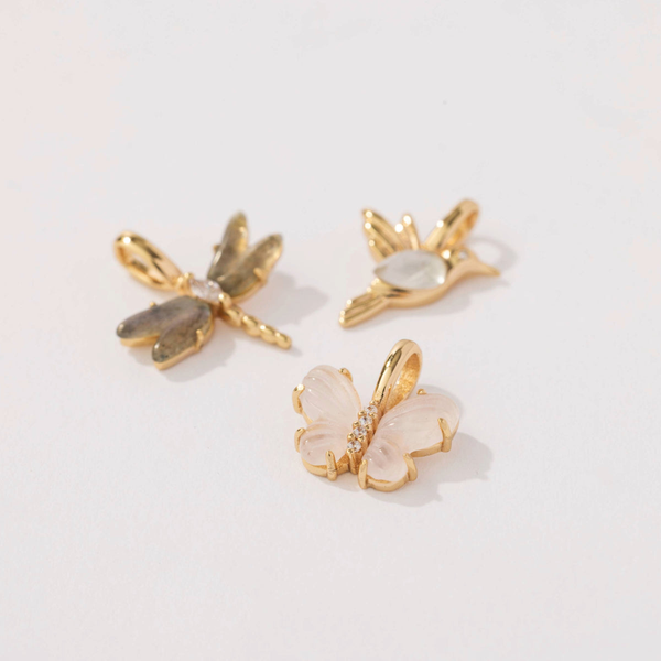 Three gold charms: a dragonfly, butterfly, and hummingbird. Each charm is inlayed with different colors of natural gemstones.