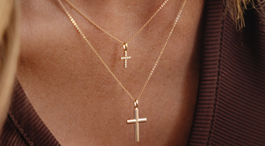 A model wearing two layered gold cross pendant necklaces.