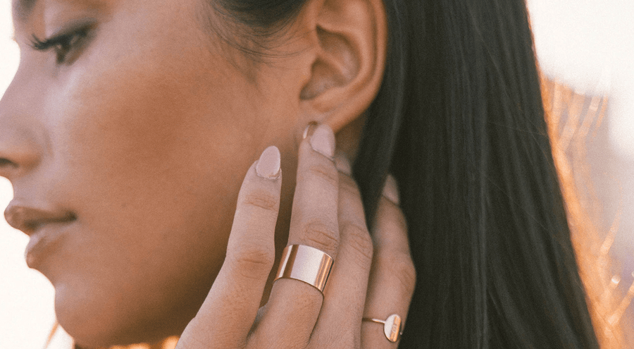A woman wearing a gold wide polished cigar band ring.