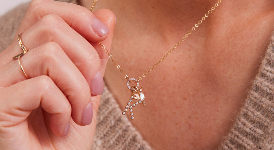 A person wearing a gold pendant chain necklace with layered charms.