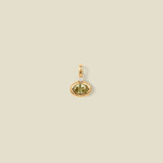 A gold pendant featuring a central oval light green gemstone and a small clear accent stone, centered on a solid beige background.