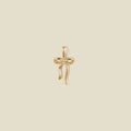 A gold bow shaped pendant charm with a small clear stone in the center.