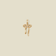 A gold bow shaped pendant charm with a small clear stone in the center.