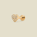 A gold heart-shaped stud earring with pave diamonds and a flat earring back, set against a light beige background.