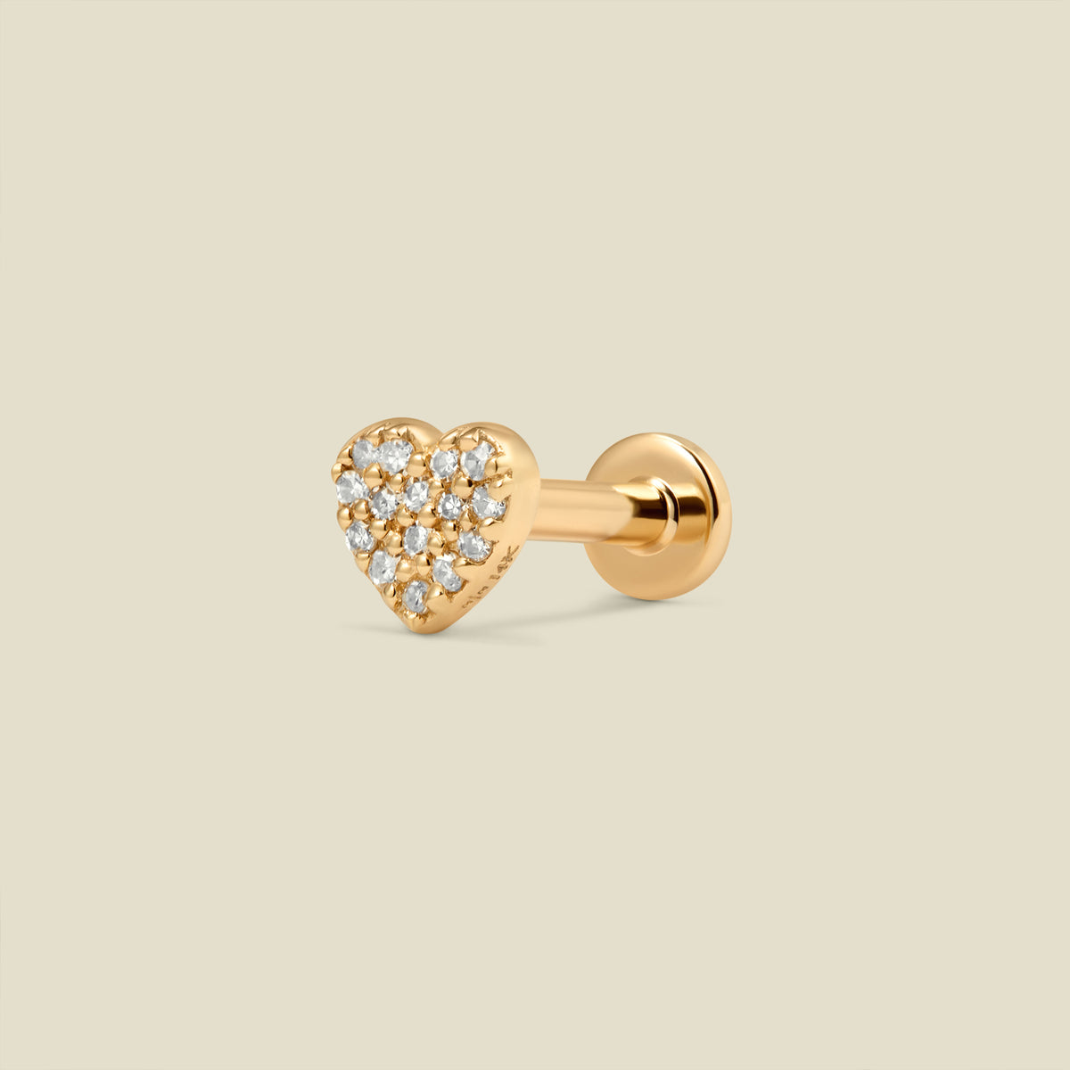 A gold heart-shaped stud earring with pave diamonds and a flat earring back, set against a light beige background.