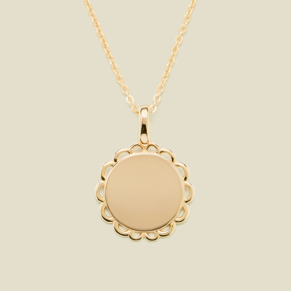 Gold necklace with a round pendant on a beige background