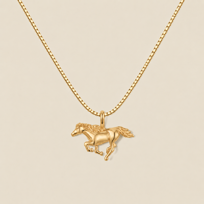 A gold running horse pendant necklace on a matching gold box chain, displayed against a solid light beige background.