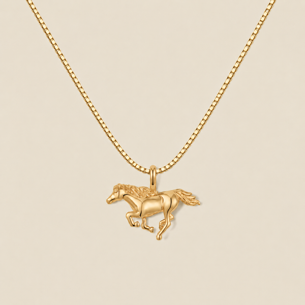 A gold running horse pendant necklace on a matching gold box chain, displayed against a solid light beige background.
