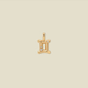 A gold pendant shaped like the Gemini zodiac symbol, featuring three small clear gemstones, centered on a solid light beige background.