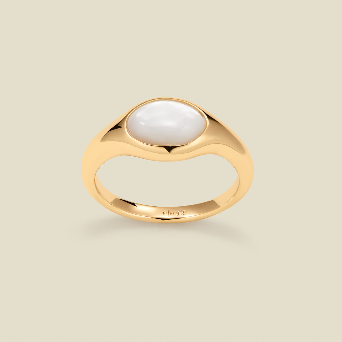 Gold ring with a bezel-set pearl stone against a neutral background.