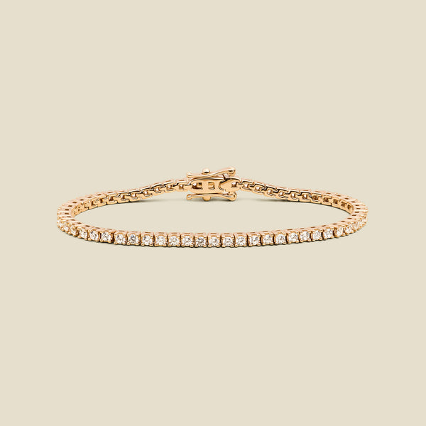 A gold tennis bracelet with clear square-cut gemstones, displayed on a solid light beige background.