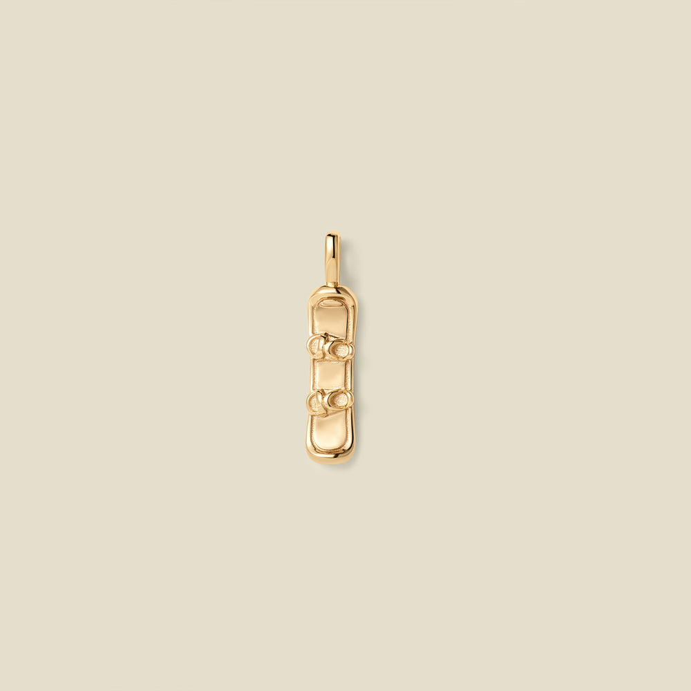 A gold pendant shaped like a snowboard with details, centered on a light beige background.