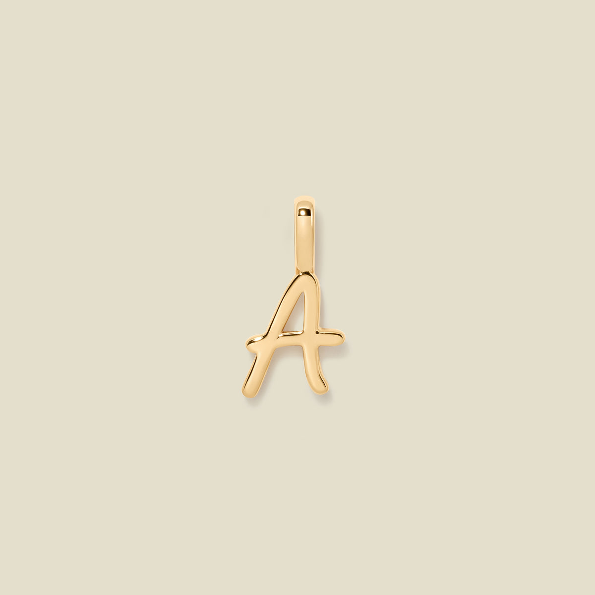 A polished gold initial pendant charm shaped like the letter 'A' in a cursive script, centered on a solid light beige background.