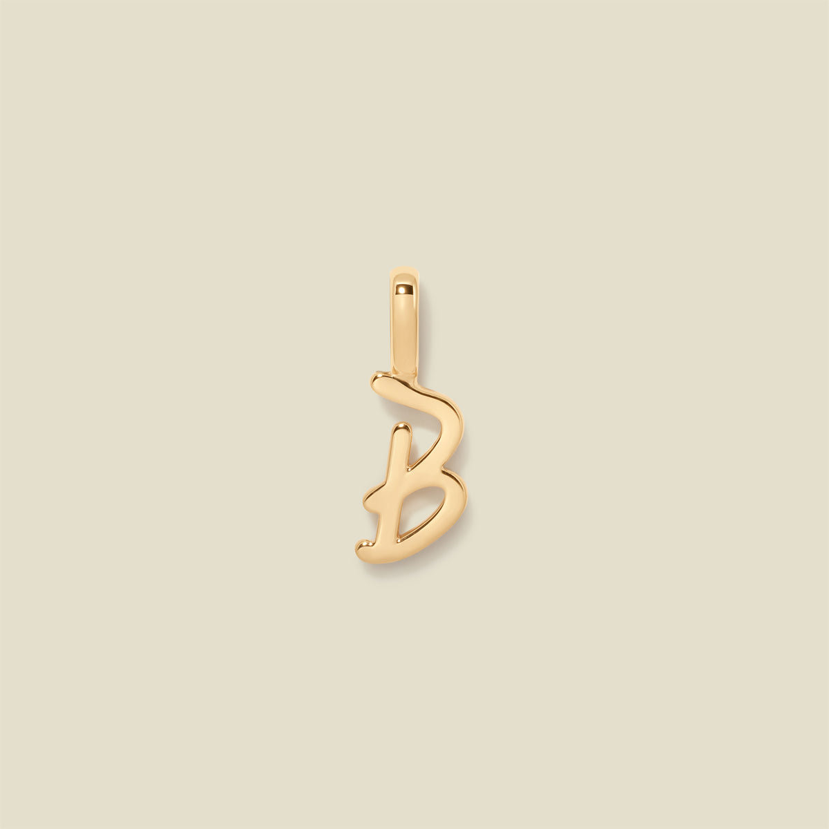 Gold initial "b" charm on a beige background