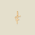 A polished gold initial pendant charm shaped like the letter 'F' in a cursive script, centered on a solid light beige background.