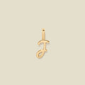 A polished gold initial pendant charm shaped like the letter 'J' in a cursive script, centered on a solid light beige background.