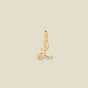 A polished gold initial pendant charm shaped like the letter 'L' in a cursive script, centered on a solid light beige background.