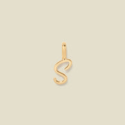 A polished gold initial pendant charm shaped like the letter 'S' in a cursive script, centered on a solid light beige background.