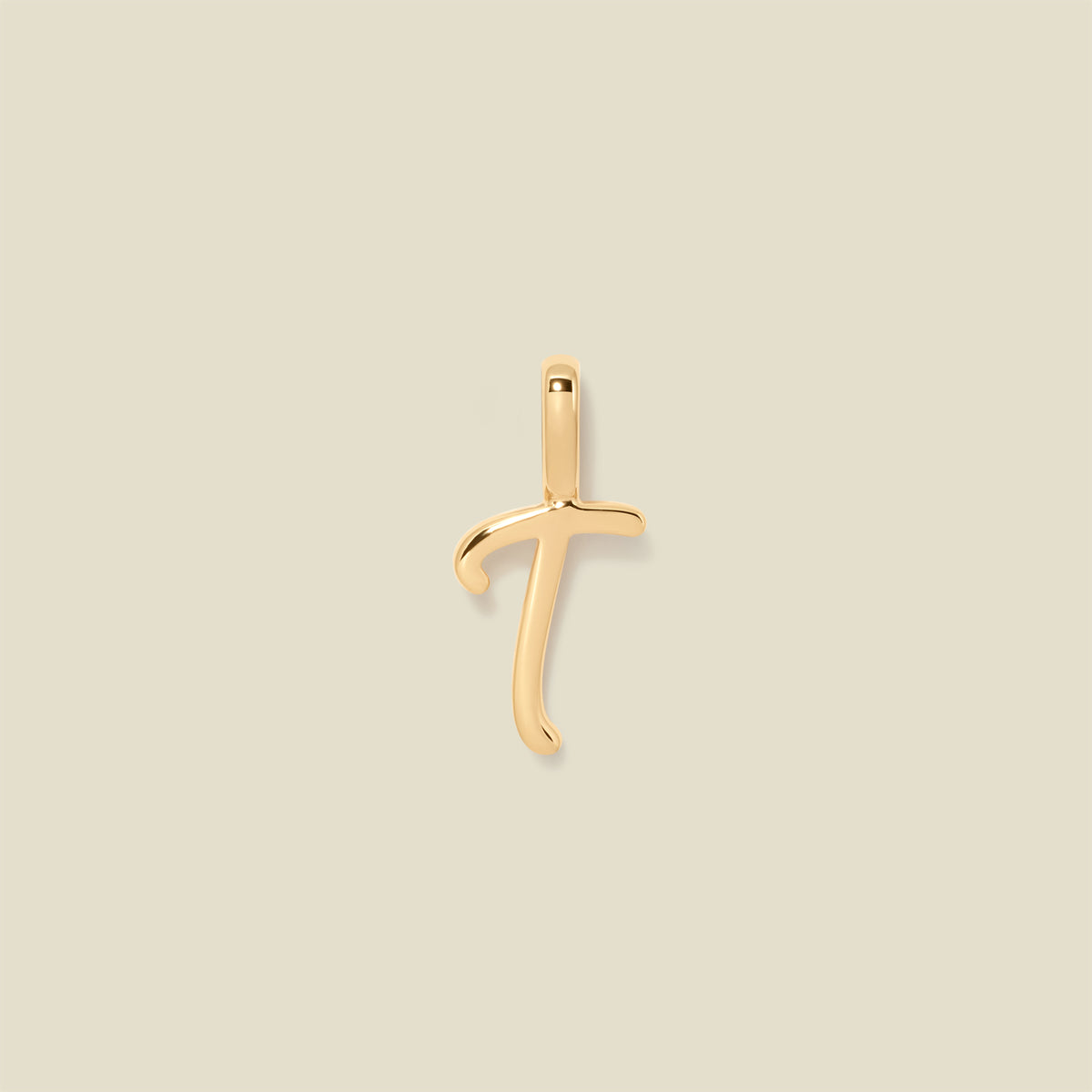 A polished gold initial pendant charm shaped like the letter 'T' in a cursive script, centered on a solid light beige background.