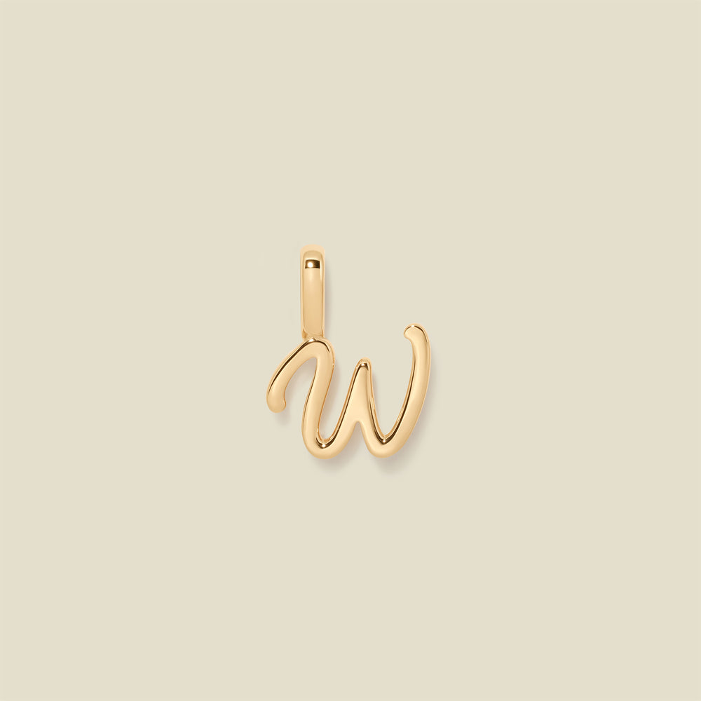 A polished gold initial pendant charm shaped like the letter 'W' in a cursive script, centered on a solid light beige background.