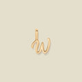 A polished gold initial pendant charm shaped like the letter 'W' in a cursive script, centered on a solid light beige background.