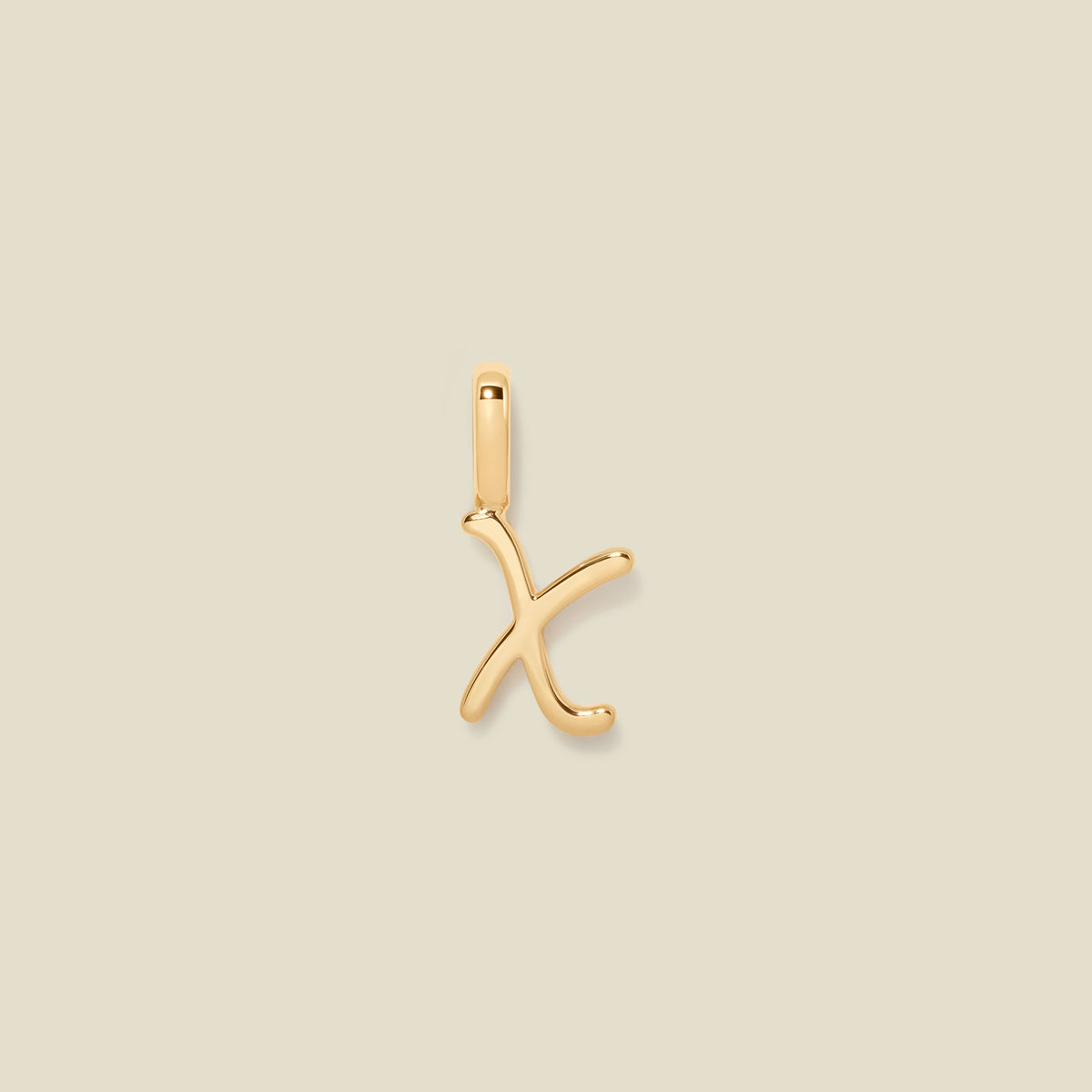 A polished gold initial pendant charm shaped like the letter 'X' in a cursive script, centered on a solid light beige background.