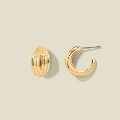 A pair of gold-toned hoop earrings on a light beige background. One earring is shown from the front, featuring a textured, ribbed oval design, while the other is shown from the side, displaying a smooth curved shape and a silver-tone post.
