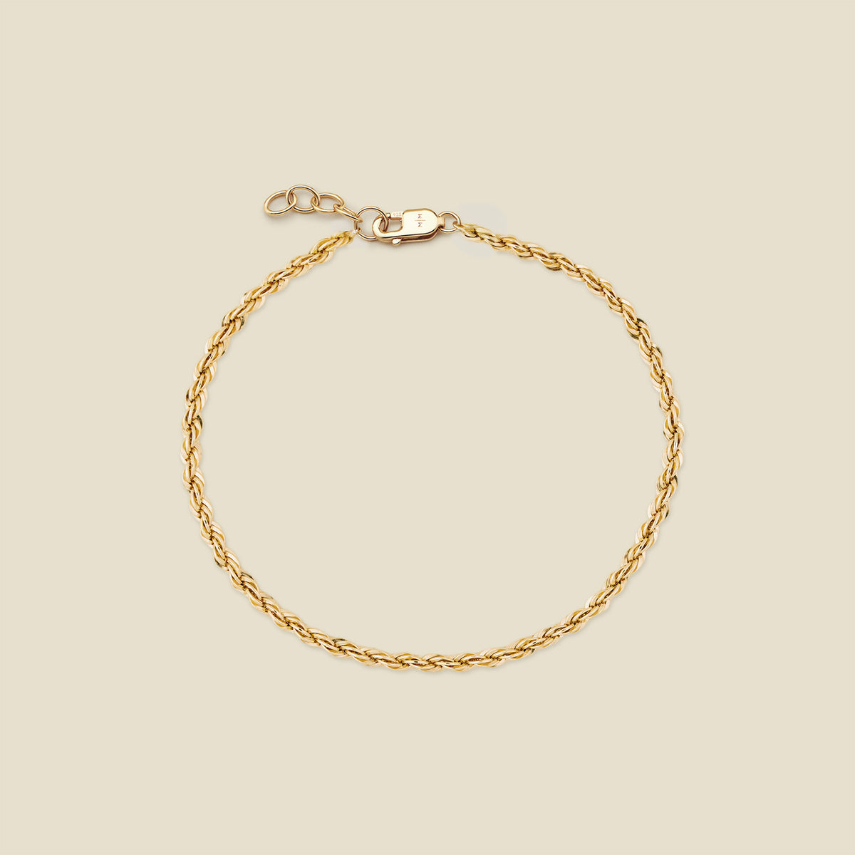 A gold rope chain bracelet with a lobster clasp and extender, displayed on a light beige background.