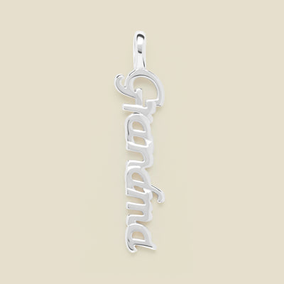A silver script font charm spelling 'Grandma' vertically, set against a solid beige background.
