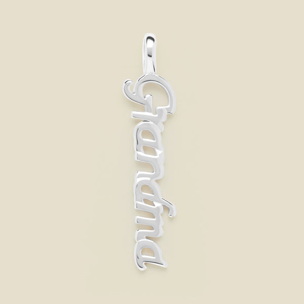 A silver script font charm spelling 'Grandma' vertically, set against a solid beige background.