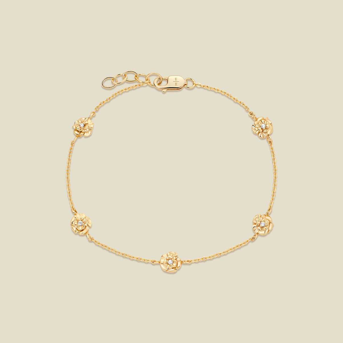 A delicate gold chain bracelet with five small, textured carnation charms spaced evenly along the chain, displayed on a solid light beige background.