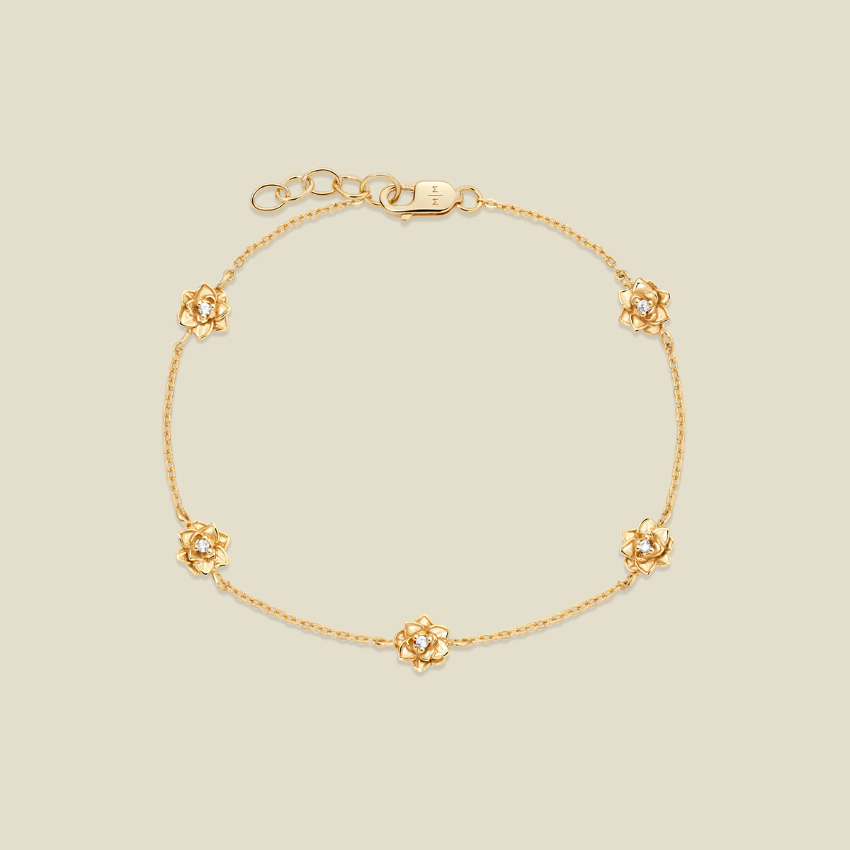 A delicate gold chain bracelet featuring five ornate, textured gold lotus charms with small clear stones, arranged in a circle on a light beige background.
