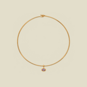 A delicate gold wire necklace with a small dangling charm featuring a light purple oval gemstone, set against a solid beige background.
